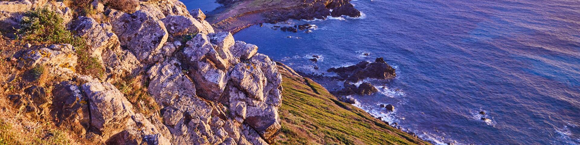 View of Pointe de la Parata on the west coast of Corsica France Europe. A ruined Genoese tower sits on top of the rocky promontory overlooking the archipelago of the Sanguinaires on the colored sunset