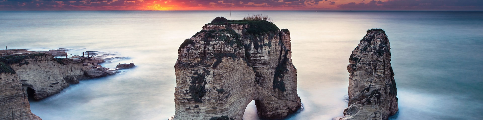 A coastal landscape with prominent rock formations during sunset.