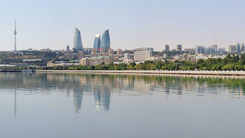 A city skyline with modern buildings, a river, and a Ferris wheel.