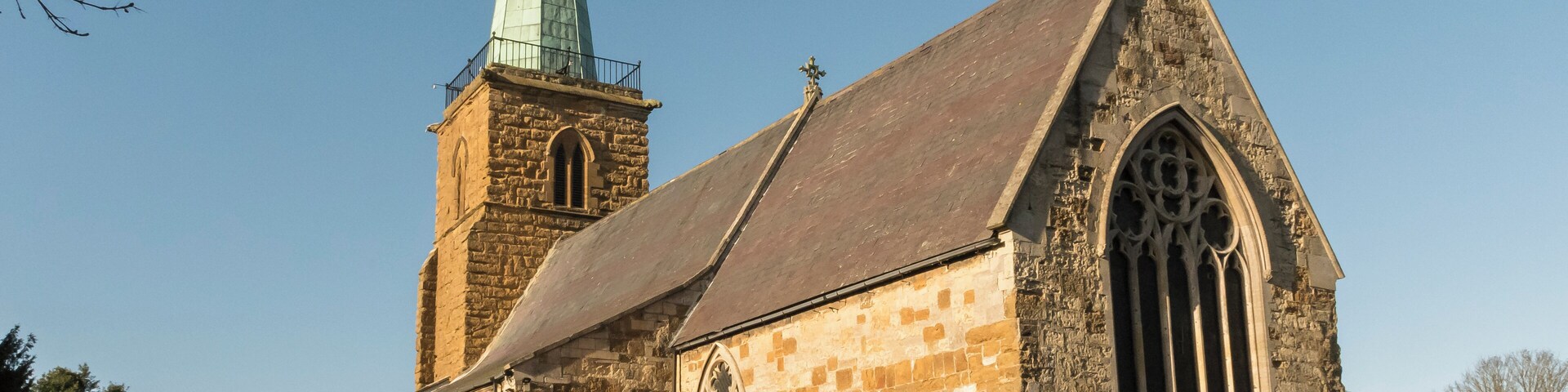 A historic church with a tall steeple and a large arched window.