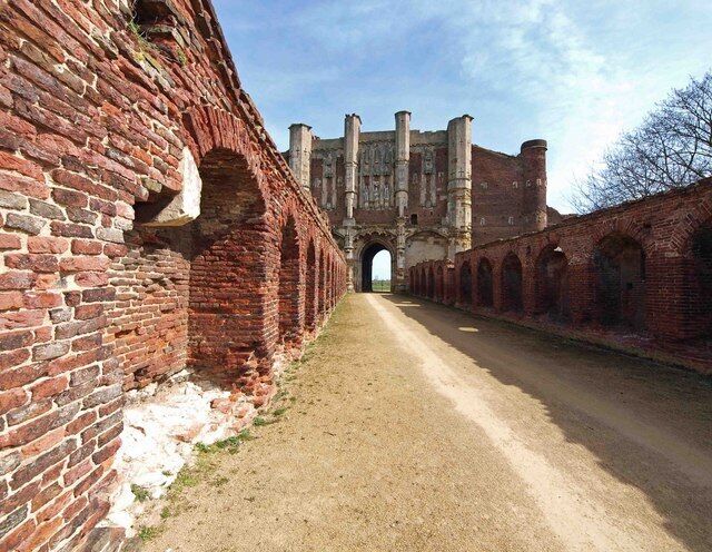 Een pad van baksteen leidt naar een historisch gebouw met booggangen en een grote poort.