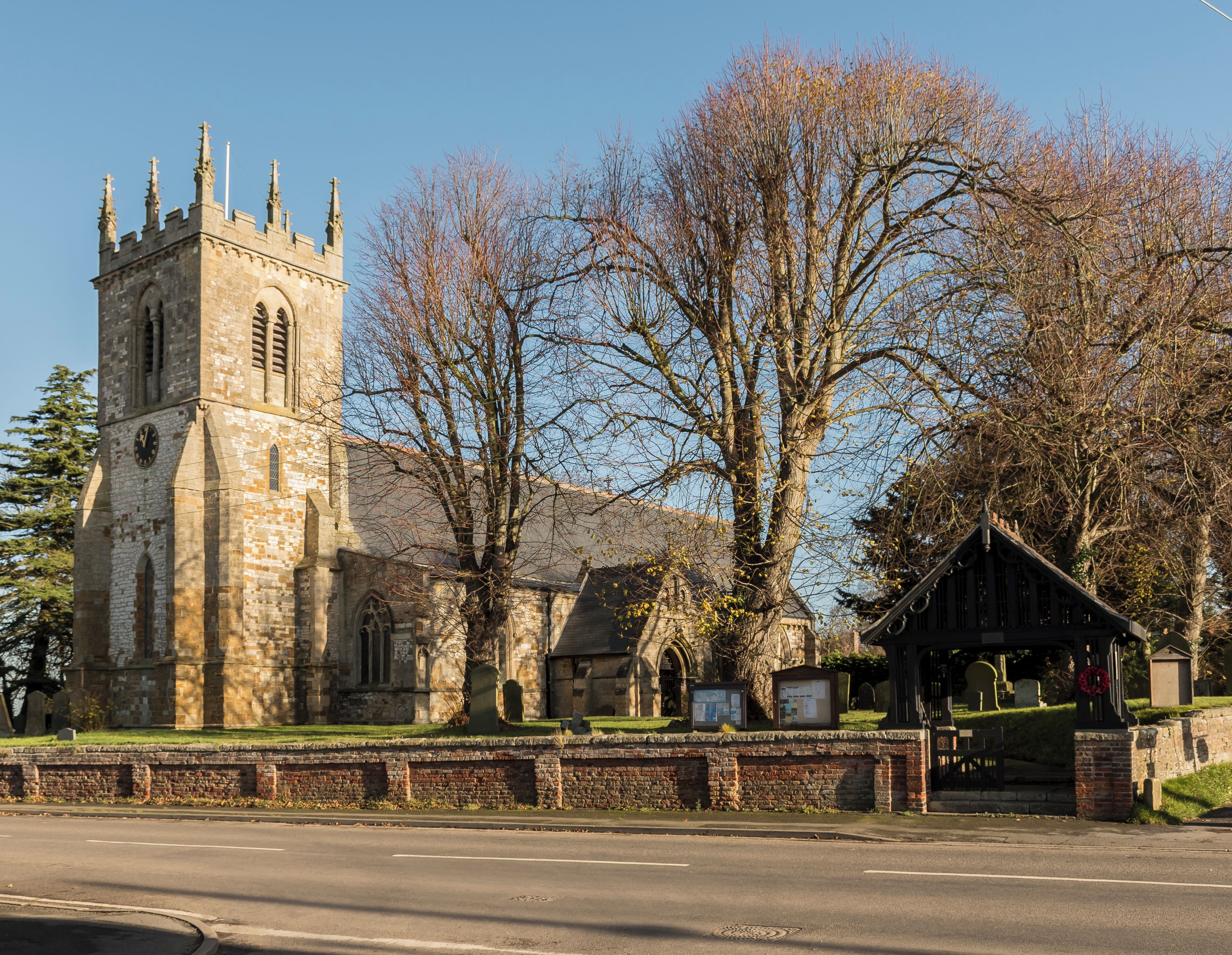 A historic church with a tall tower and a large tree in front.