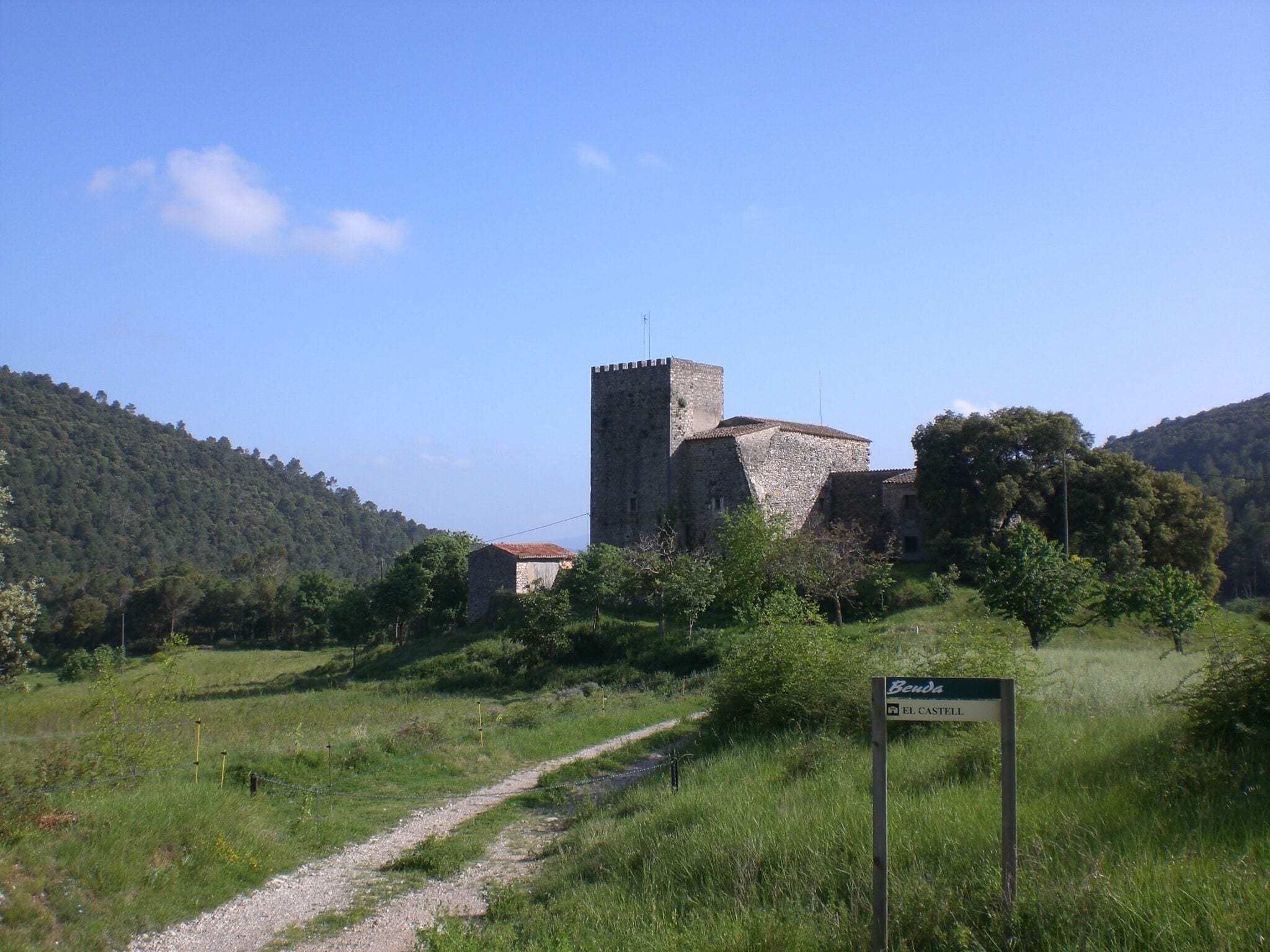 A medieval castle surrounded by lush green hills and a clear blue sky.