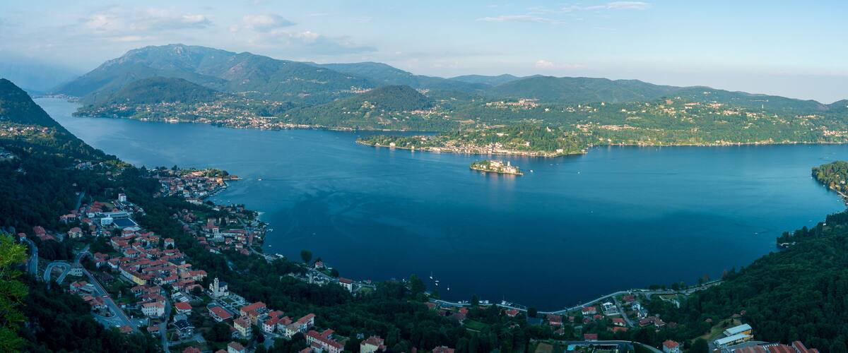 A coastal town with a bay, surrounded by mountains and dense forests.
