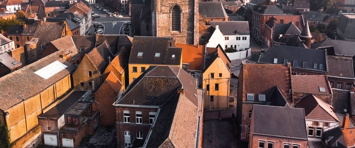 A historic town with a prominent church tower, dense medieval architecture, and a cobblestone street.