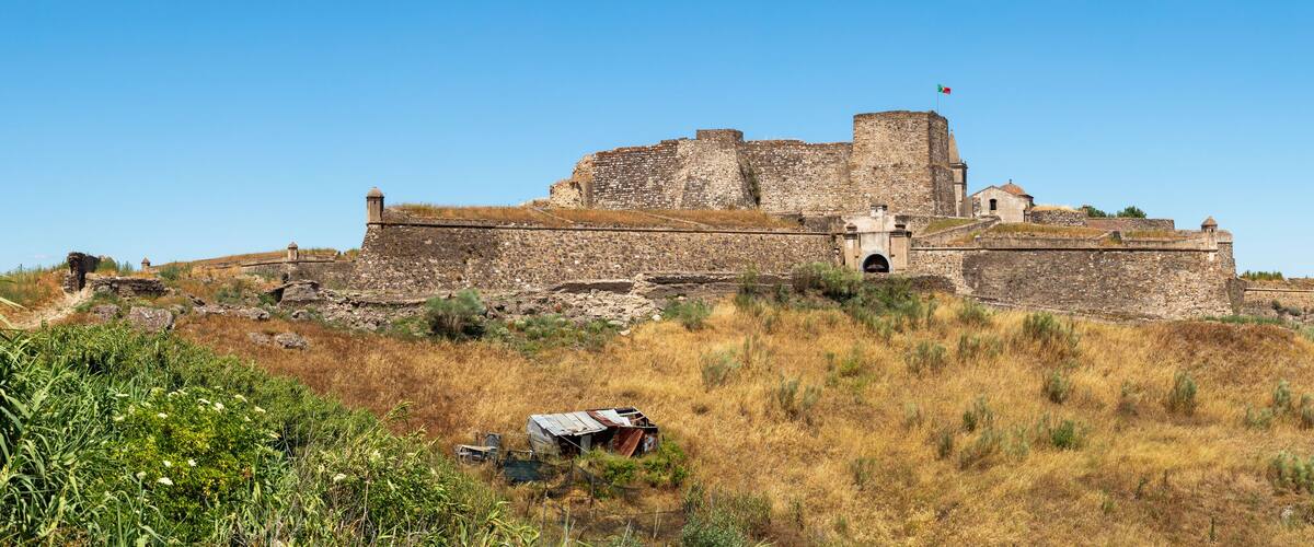 A historic stone castle on a hill overlooking a river.