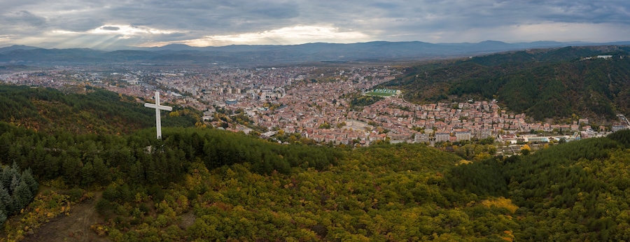 A cityscape with a prominent cross on a hill overlooking a densely populated area.