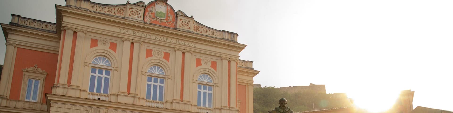 A historic building with arched windows and a statue in front.