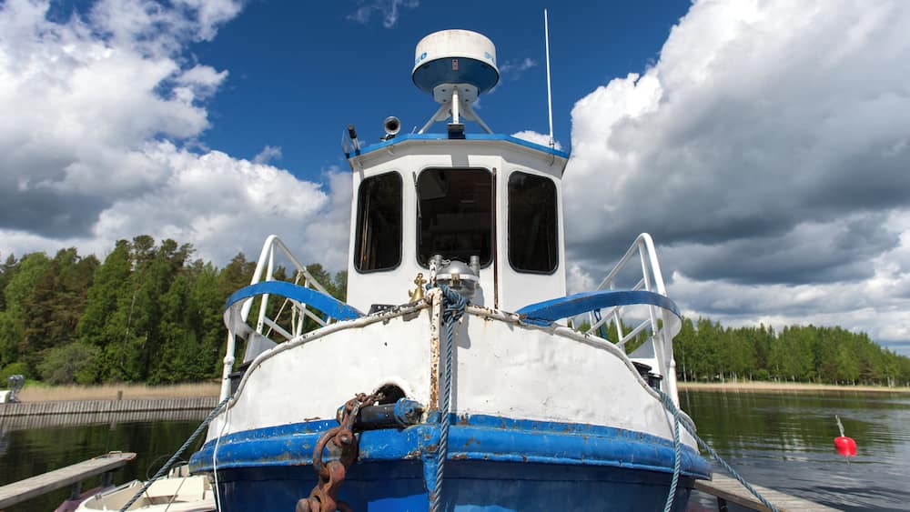 A boat docked at a pier with a forest in the background.