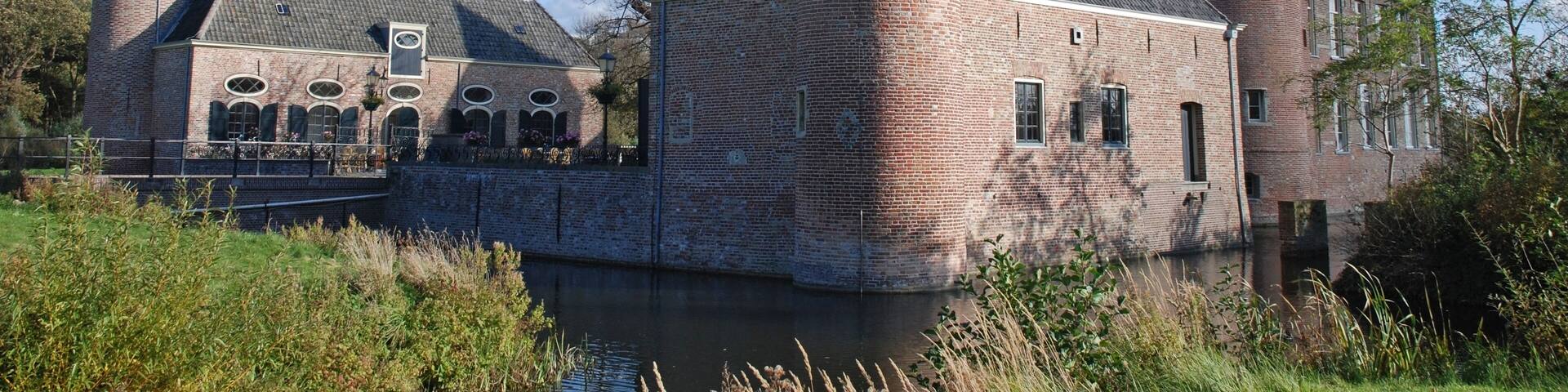 A historic brick castle with two towers, a moat, and a bridge.