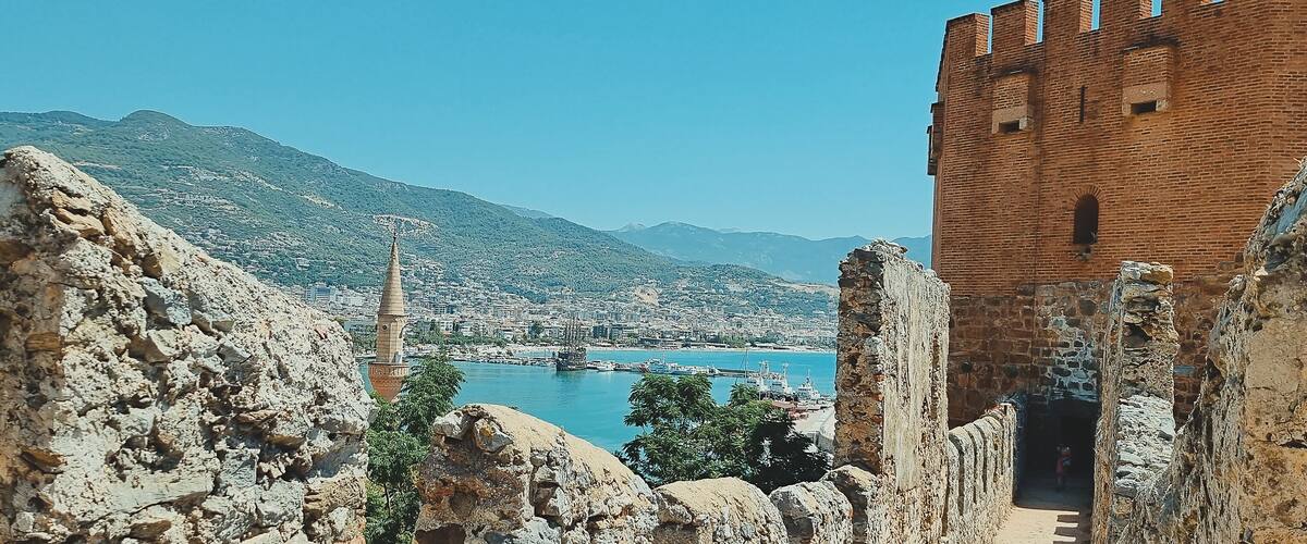 A coastal city with a prominent tower, rocky cliffs, and a historic brick building.