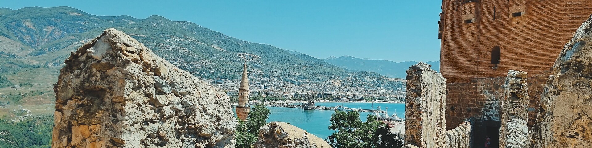 A coastal city with a prominent tower, rocky cliffs, and a historic brick building.