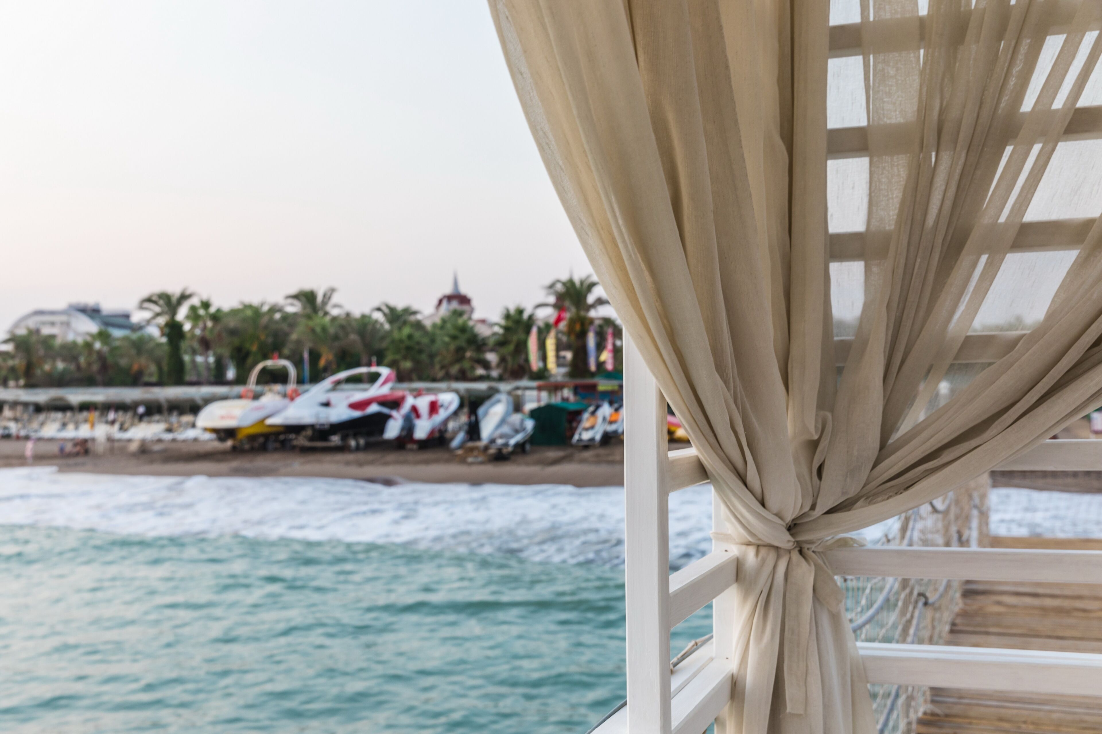beige curtain on the background of the beach of the Mediterranean Sea at sunset