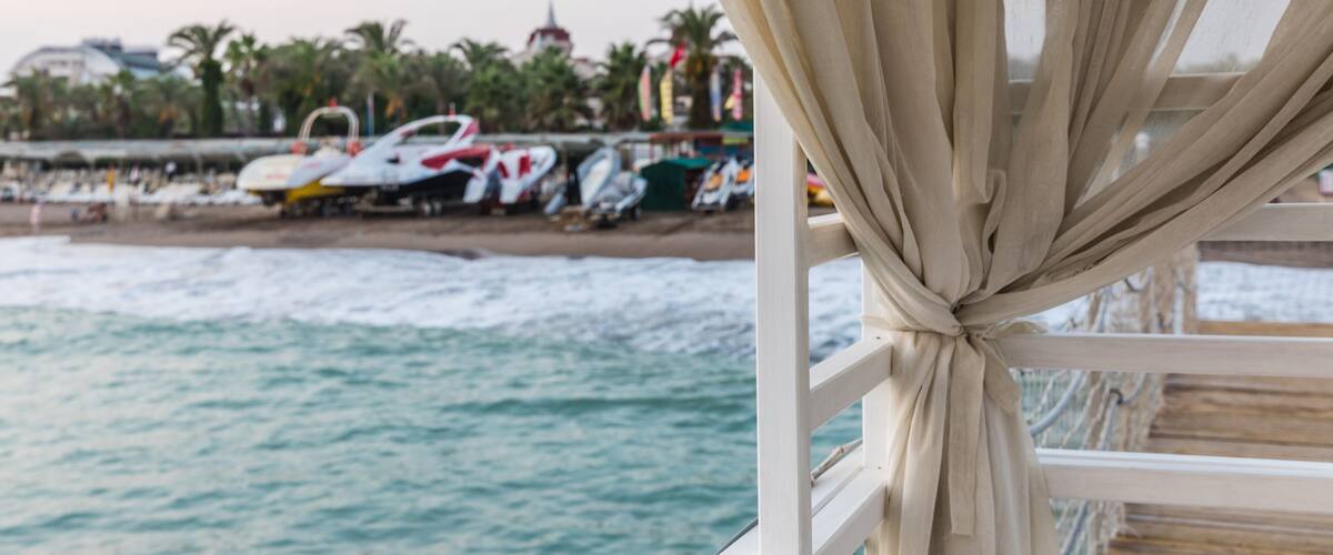 beige curtain on the background of the beach of the Mediterranean Sea at sunset