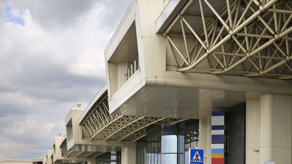 A modern building with a geometric facade and a pedestrian crossing sign.