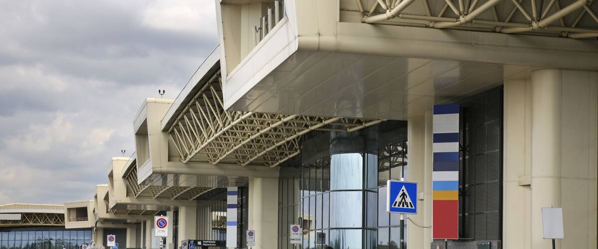 A modern building with a geometric facade and a pedestrian crossing sign.