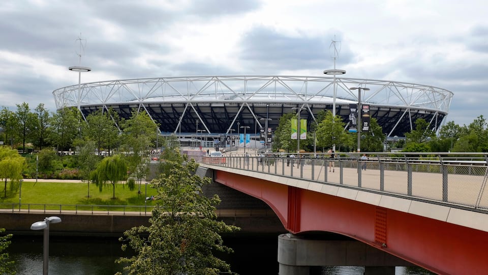 Ein Stadion mit einer roten Brücke über einem Fluss.