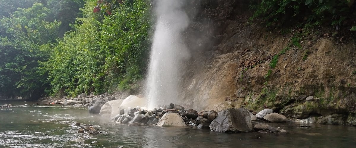 A waterfall in a forested area with clear water and rocks at the base.