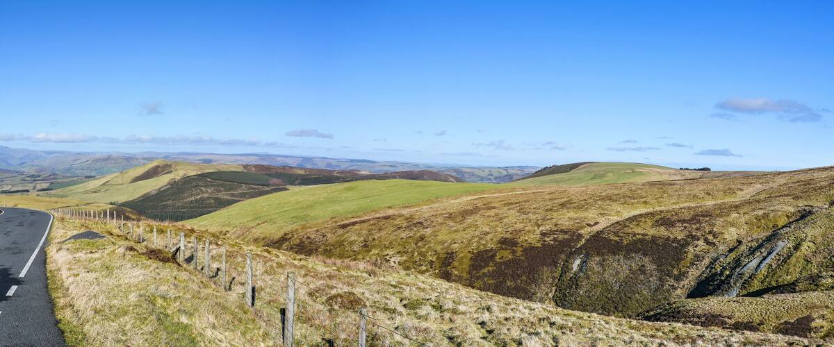A winding road through rolling hills with a clear blue sky.