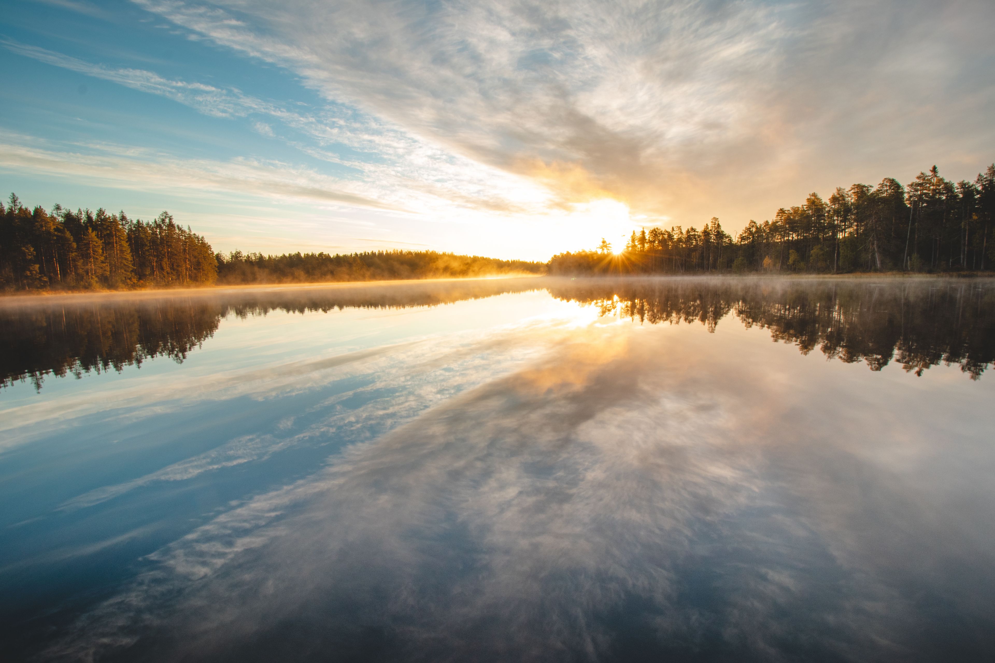 A calm lake reflecting the sky and trees.