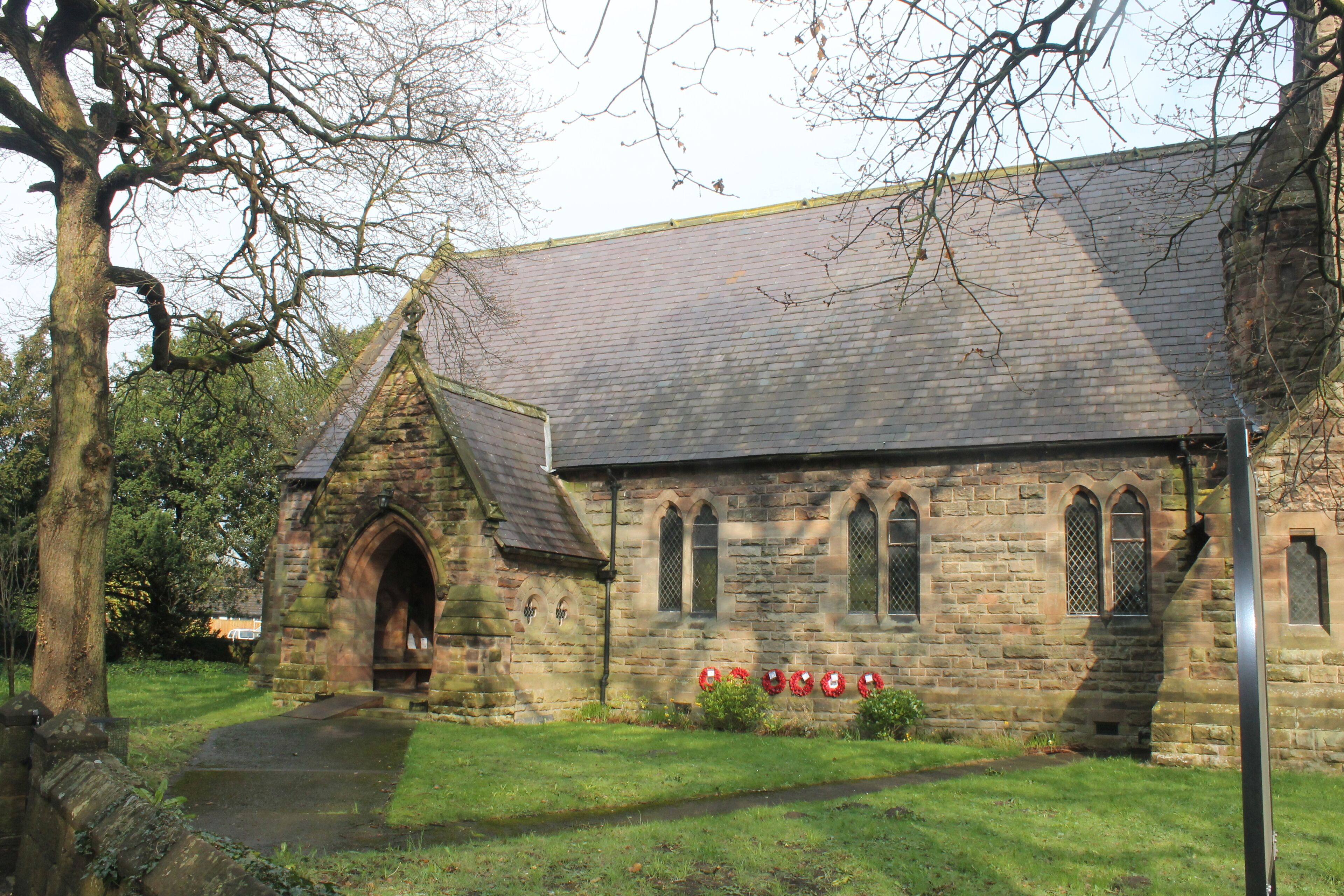 A stone church with a large arched entrance and a tiled roof.