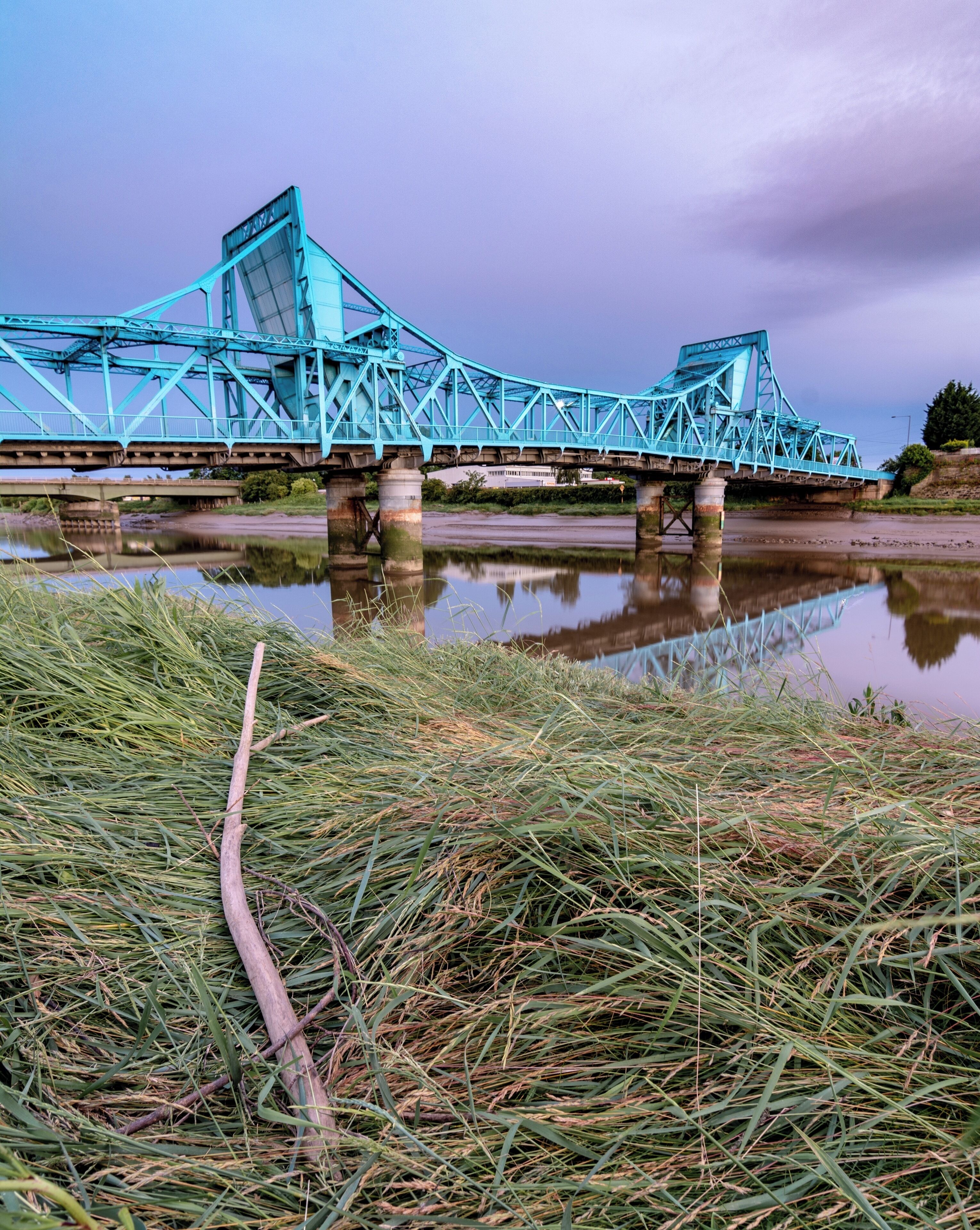The Jubilee Bridge in Queensferry, Deeside, North Wales. We used to drive over the "Blue Bridge" a few times a week as a kid on our way to see my Nan. It's has Grade 2 listed status, originally a double leaf rolling bridge but now a permanent road bridge over the River Dee. Photo taken from the North bank along the North Wales cycle path.

The branch in this photo really has no right to be there, but I did find it there rather than adding it myself! I was hoping for some light trails over the bridge as it got darker, but there's a barrier at just the right height across the whole bridge that blocks the view.

VLOG coming soon!

#deeside #jubileebridge #queensferry #northwales #northeastwales #riverdee #deeestuary #bvsblue #bluehour #reflections #rivercrossing #wideangle #clouds #d7100 #tokina1116 #darkskies #bluebridge