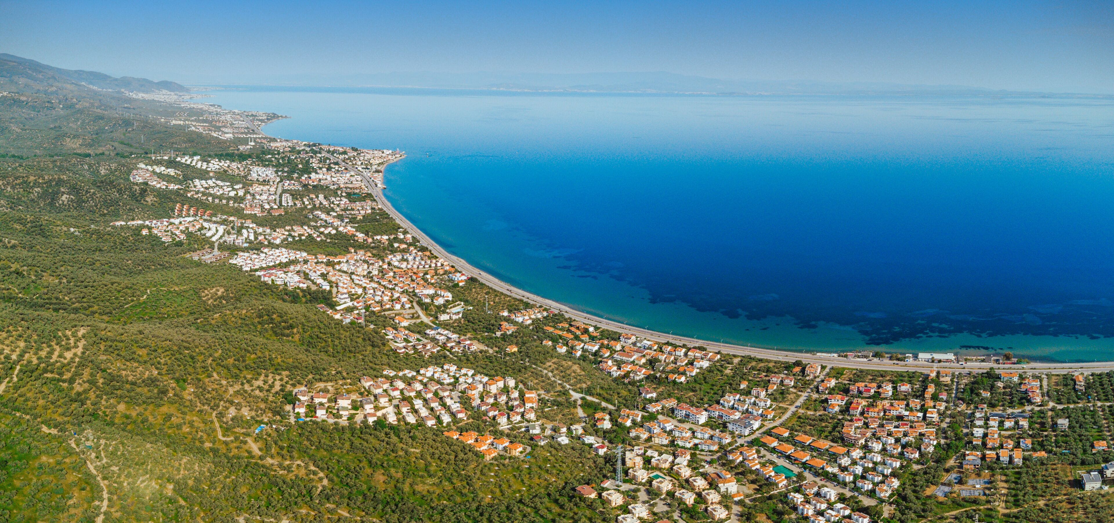 Aerial view of Altinoluk town in Edremit district of Balikesir, Turkey showing coastline, mountains and residential areas on sunny day