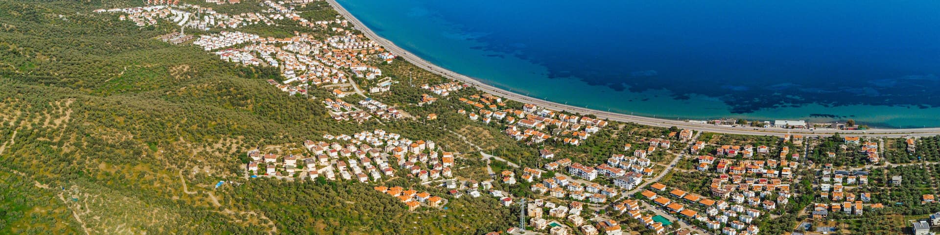 Aerial view of Altinoluk town in Edremit district of Balikesir, Turkey showing coastline, mountains and residential areas on sunny day