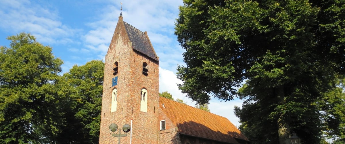A historic church with a tall bell tower and a red-tiled roof.