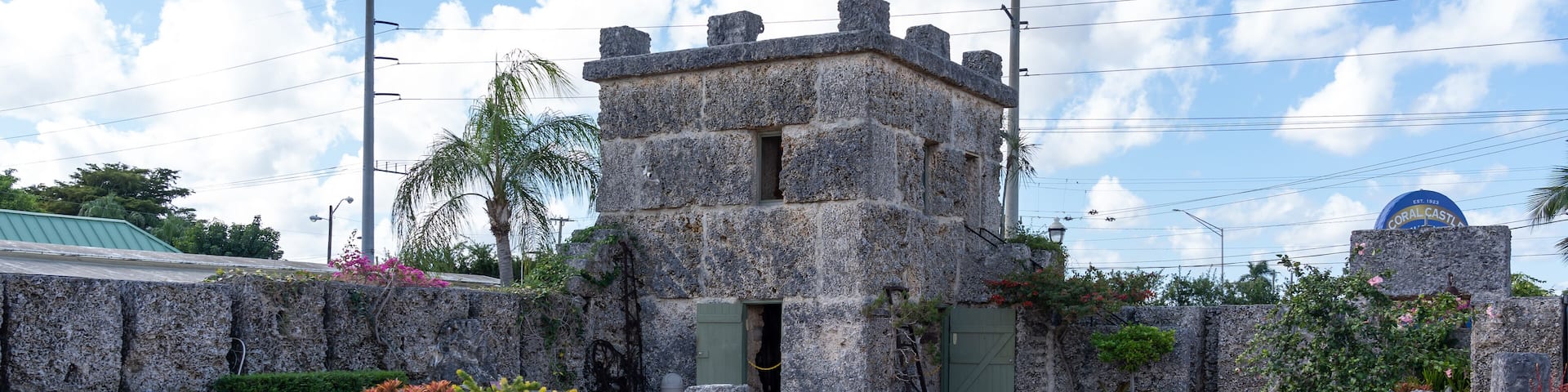A stone building with a green roof, surrounded by rocks and plants.