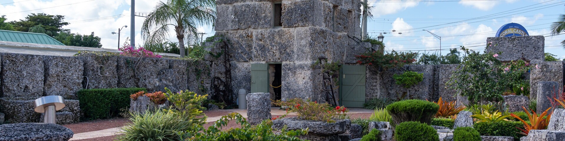 Un edificio de piedra con techo verde, rodeado de rocas y plantas.