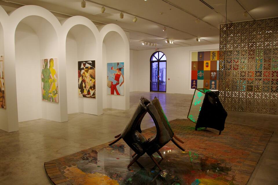 An art gallery with white walls, multiple arches, and various artworks displayed.