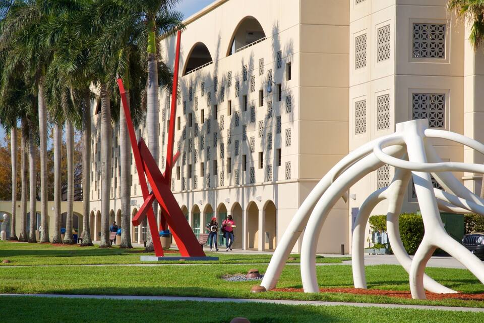A building with arched windows and a red sculpture in a landscaped area.