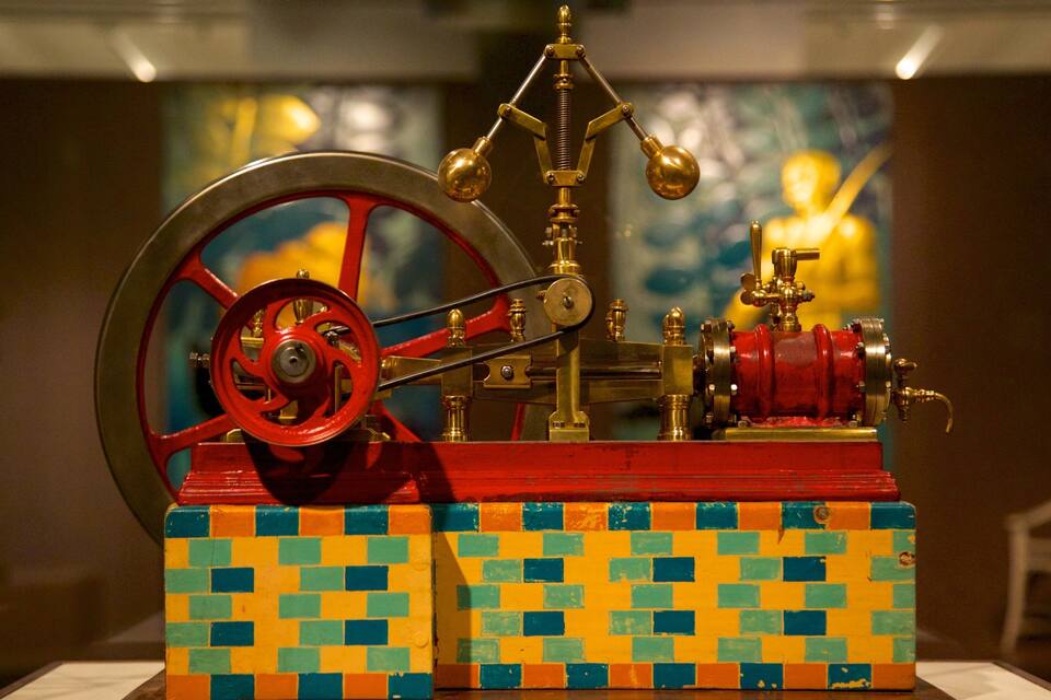 A mechanical device with a red wheel and brass components.