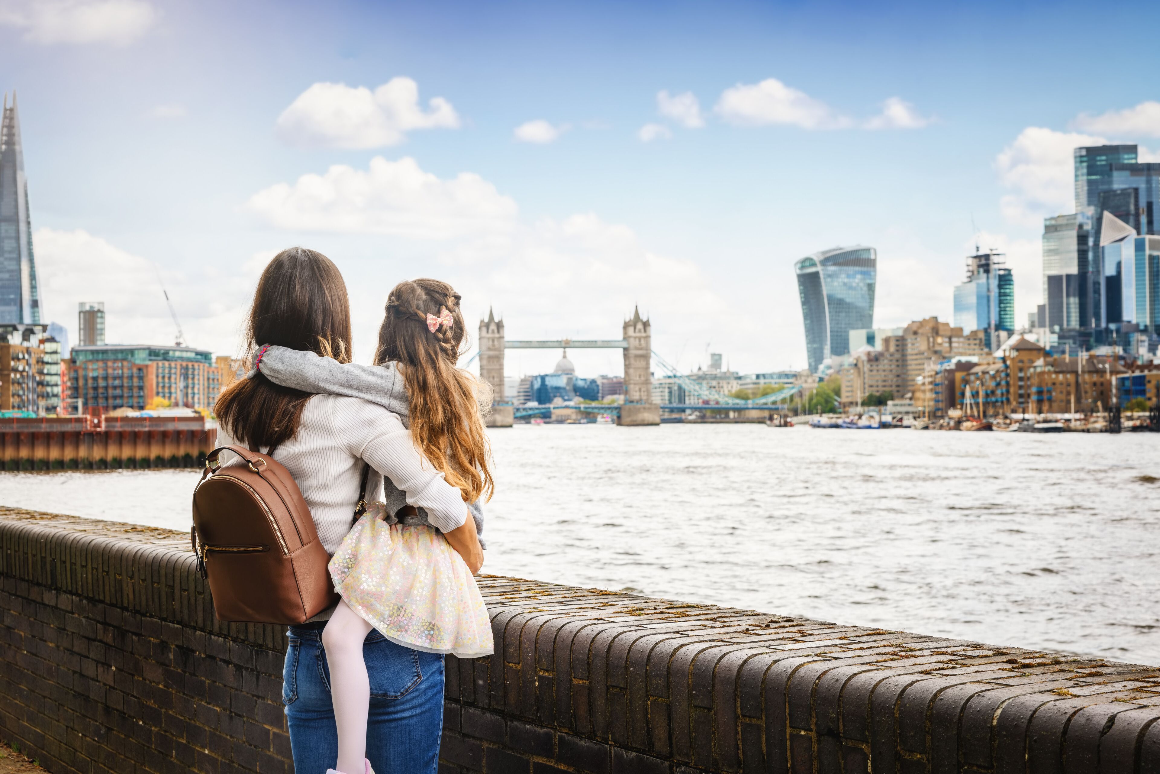 A mother and daughter on a city vacation looking at the skyline of London, England, with river Thames and Tower Bridge
