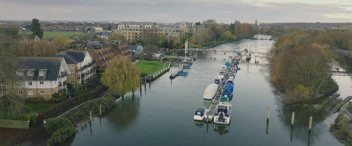 A canal with boats, buildings, and trees along the banks.