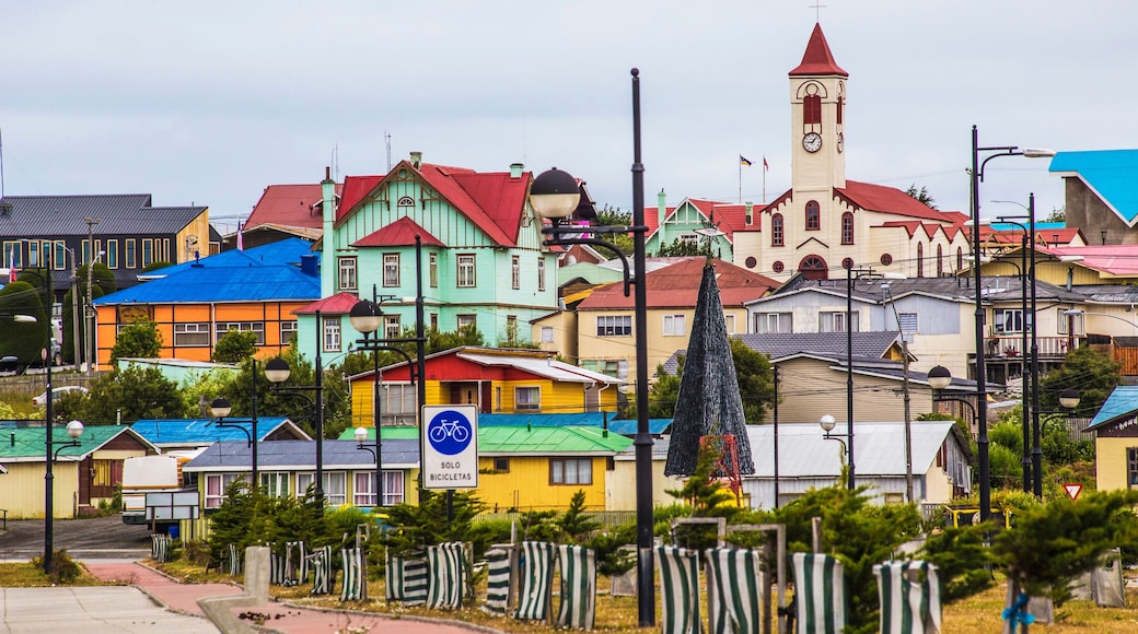 Une ville aux couleurs vives, avec un clocher d’église imposant, une variété de maisons aux façades peintes de couleurs vives, et un panneau indiquant un itinéraire cyclable.
