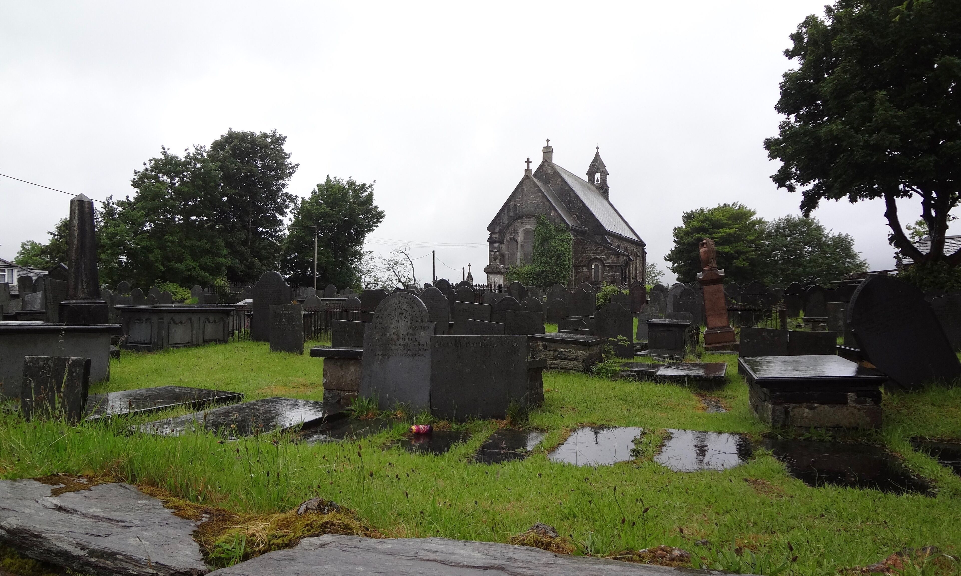 A cemetery with gravestones, a church, and a stone cross.
