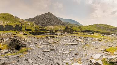 A rocky landscape with ruins and a prominent pyramid-like structure.