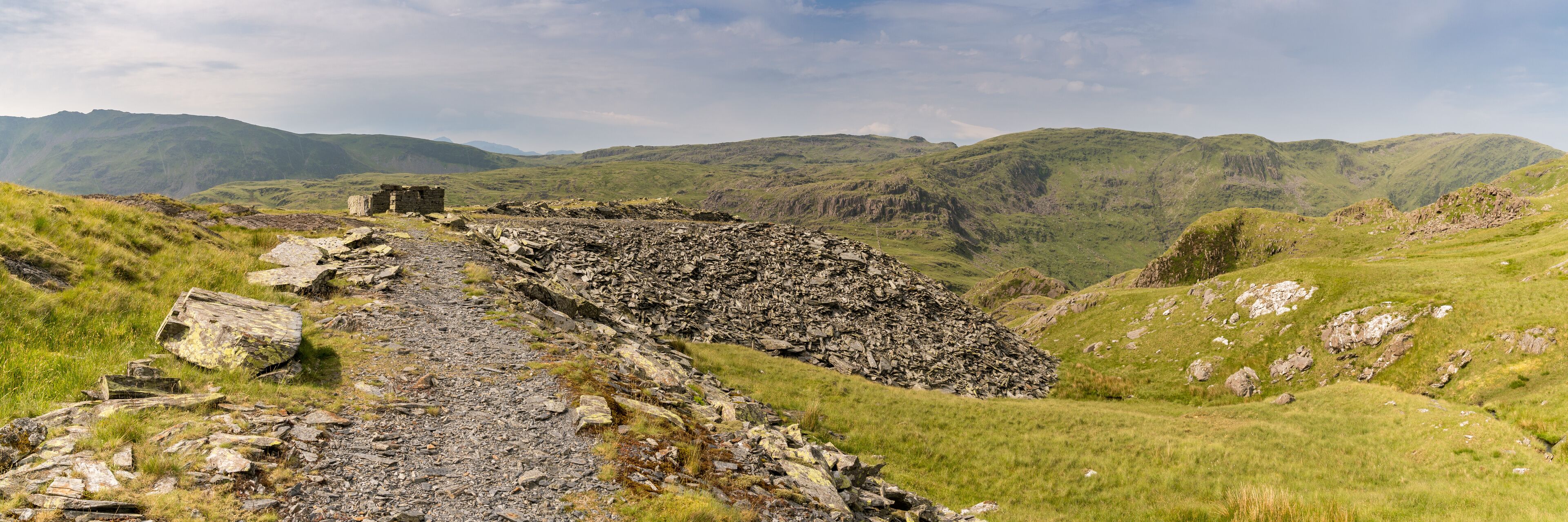 A rocky path leading to a stone structure in a mountainous landscape.