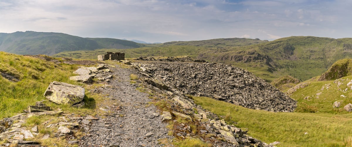 A rocky path leading to a stone structure in a mountainous landscape.