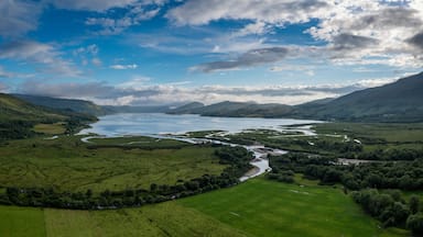 A river winding through a valley with surrounding hills and a partly cloudy sky.