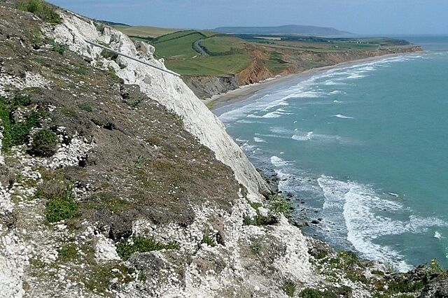 A coastal cliff with a beach and ocean.