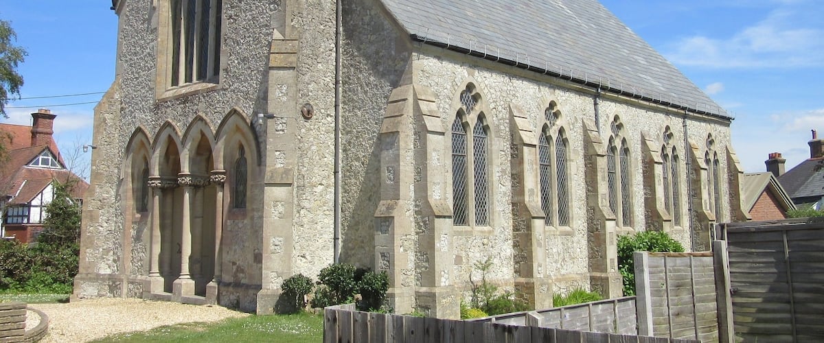 A stone church with a steeply pitched roof and arched windows.