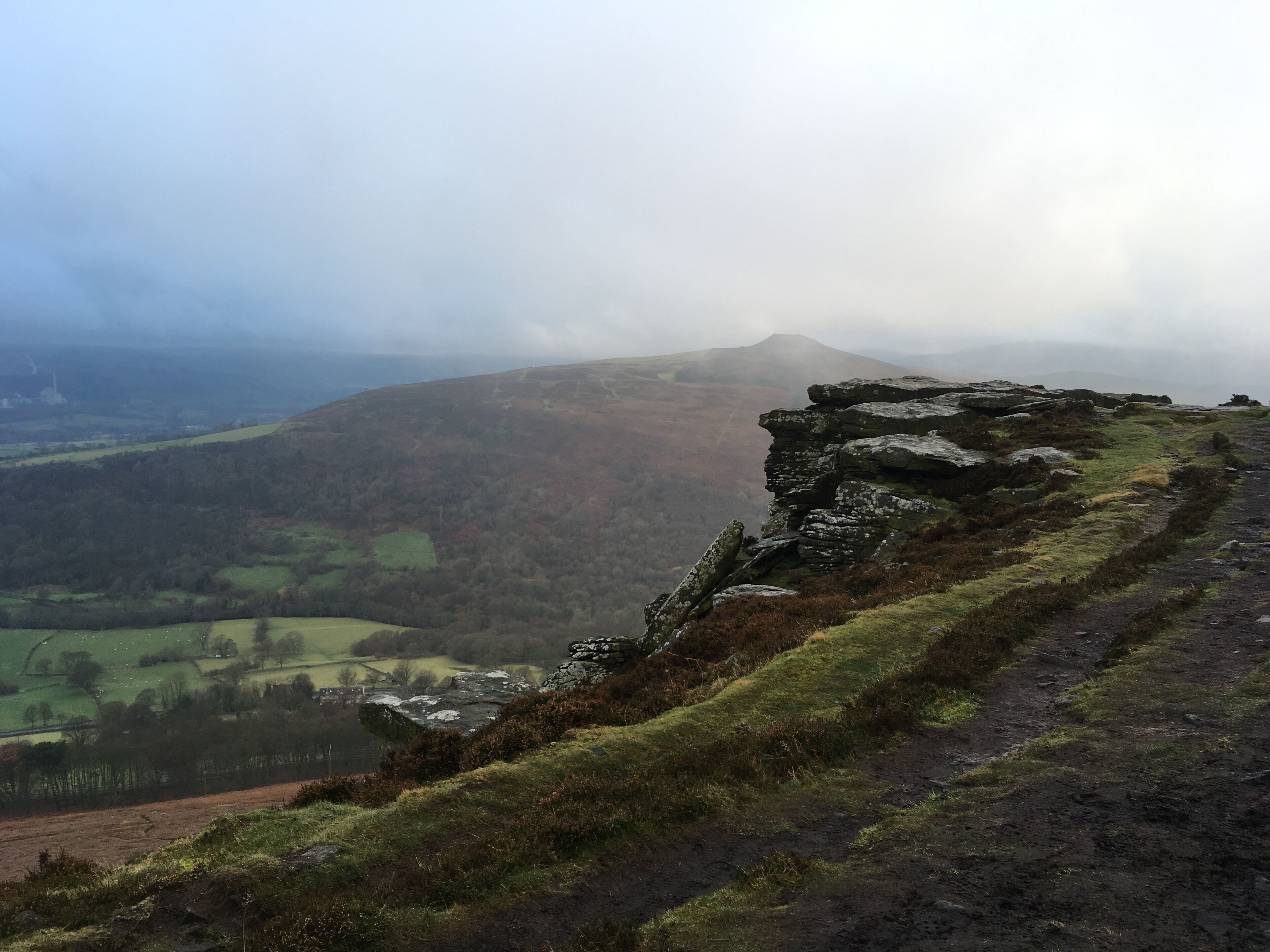 A rugged mountain ridge with a rocky outcrop and a valley below.
