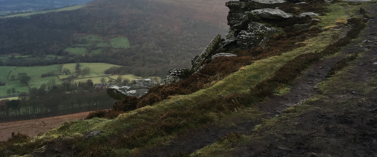A rugged mountain ridge with a rocky outcrop and a valley below.