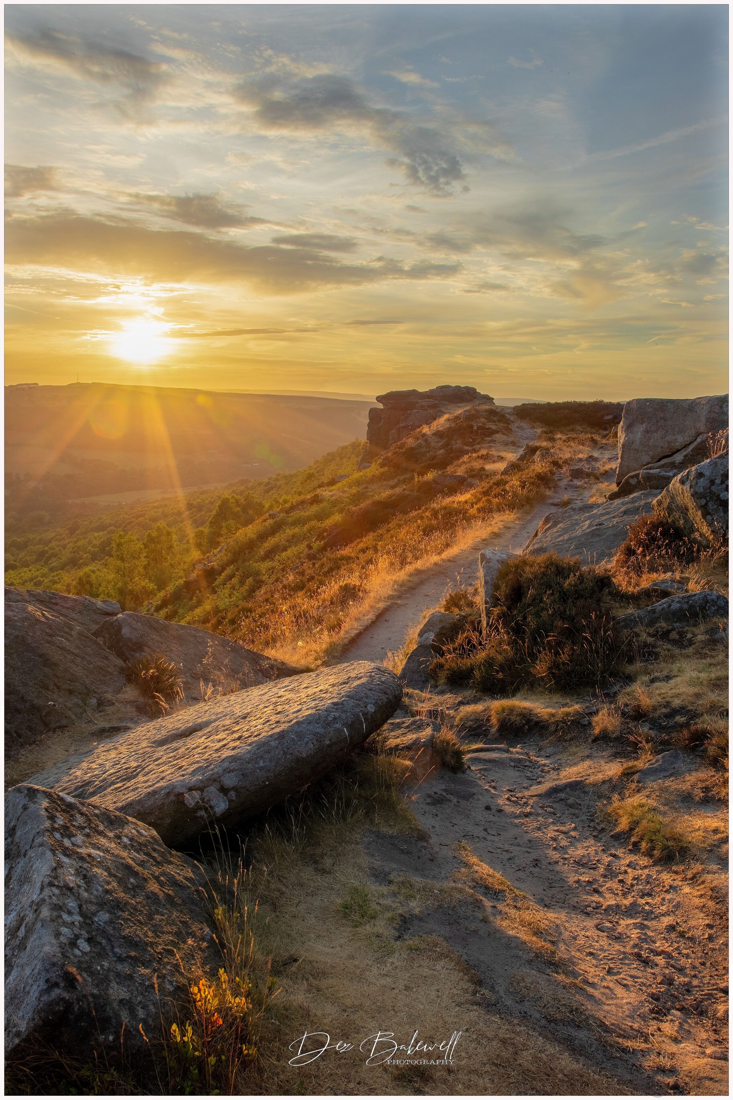 A sunset over a rocky landscape with a dirt path.