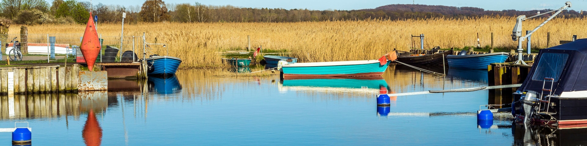Una vía acuática tranquila con barcos, boyas y un paisaje distante.