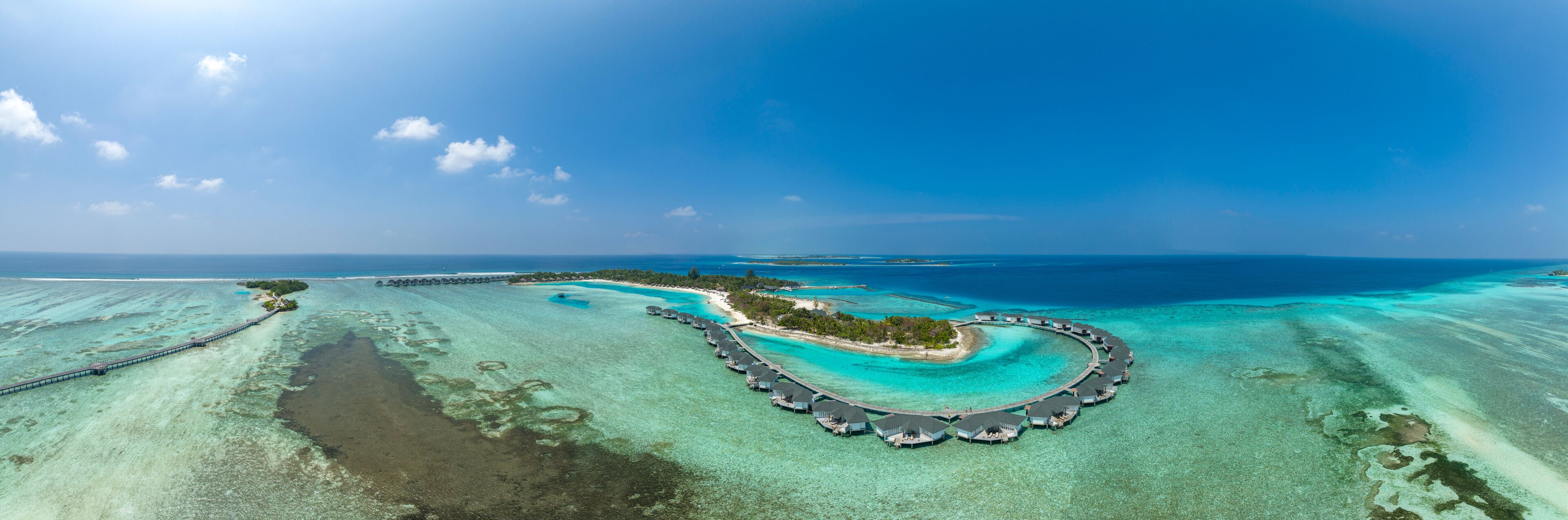 An aerial view of a tropical island resort with overwater bungalows and clear turquoise waters.