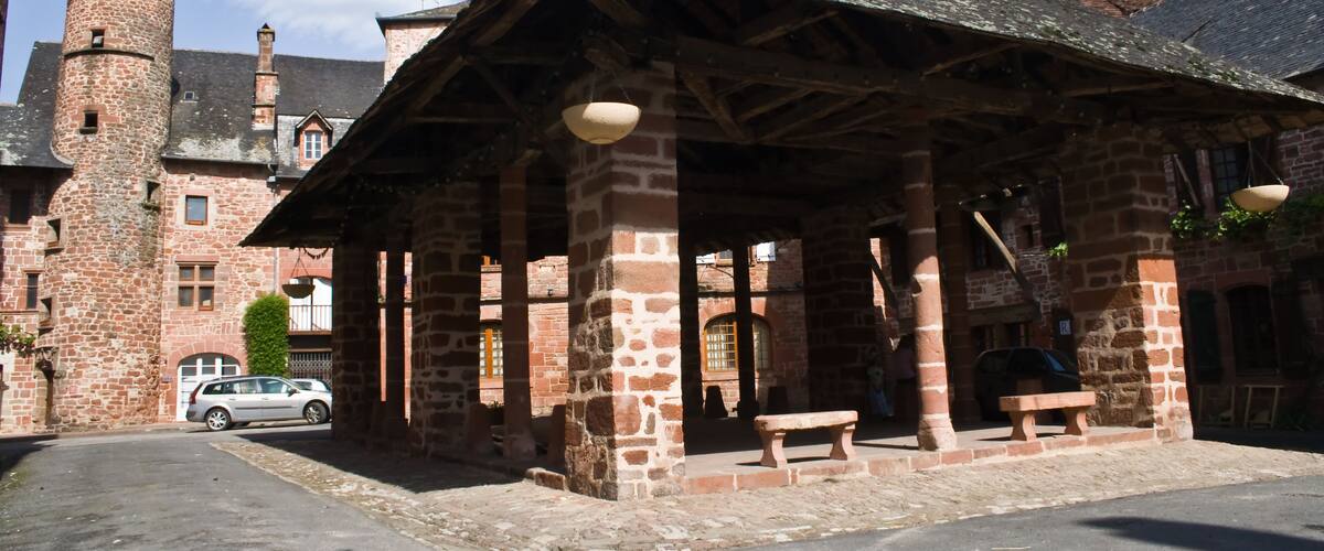 A historic stone building with a tower, a covered pavilion, and a cobblestone street.